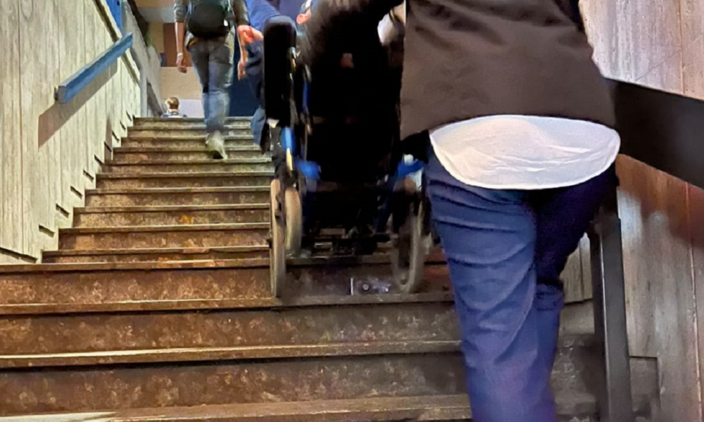 Disabile in carrozzina trasportato in braccio per le scale della metropolitana