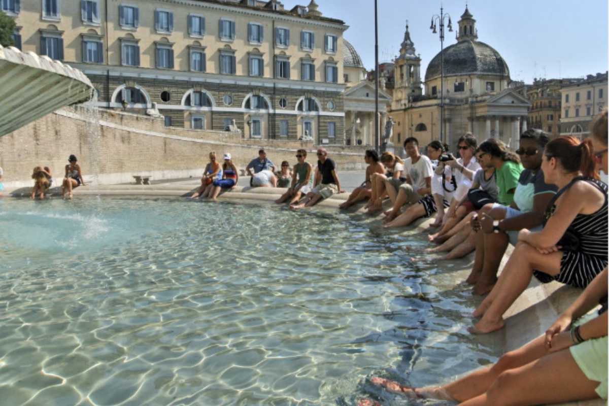 Turisti mettono i piedi nella fontana di piazza del Popolo a Roma